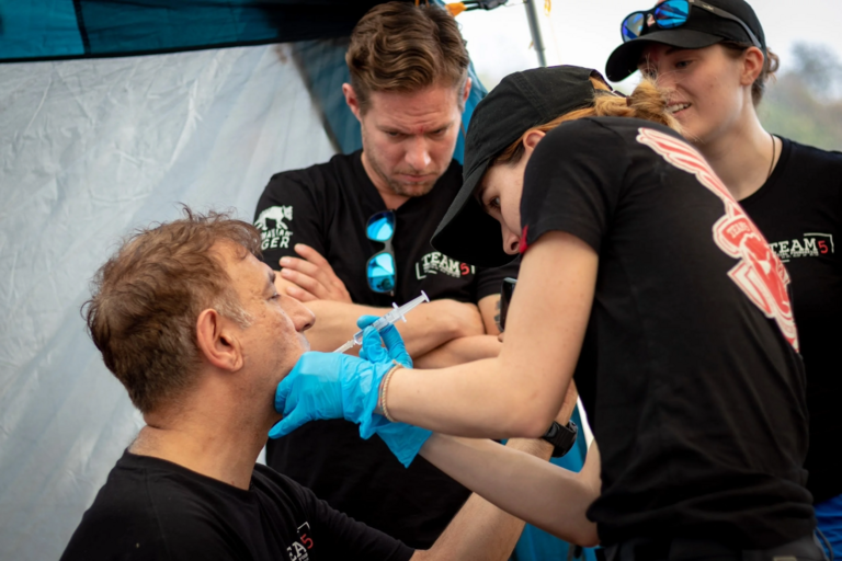 Students representing Team 5 Foundation, an organization that collaborates with the School of Public Health, provide medical care to a patient in a remote region of the world.